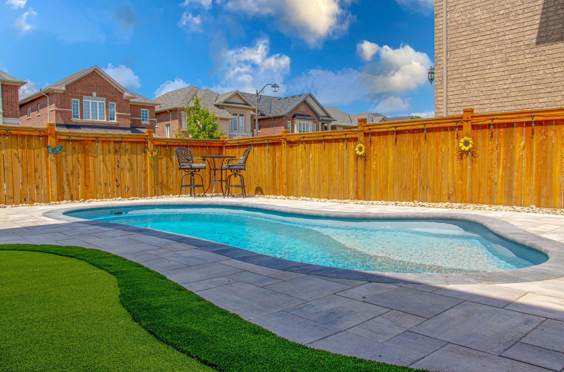 A large swimming pool surrounded by a wooden fence in a backyard.