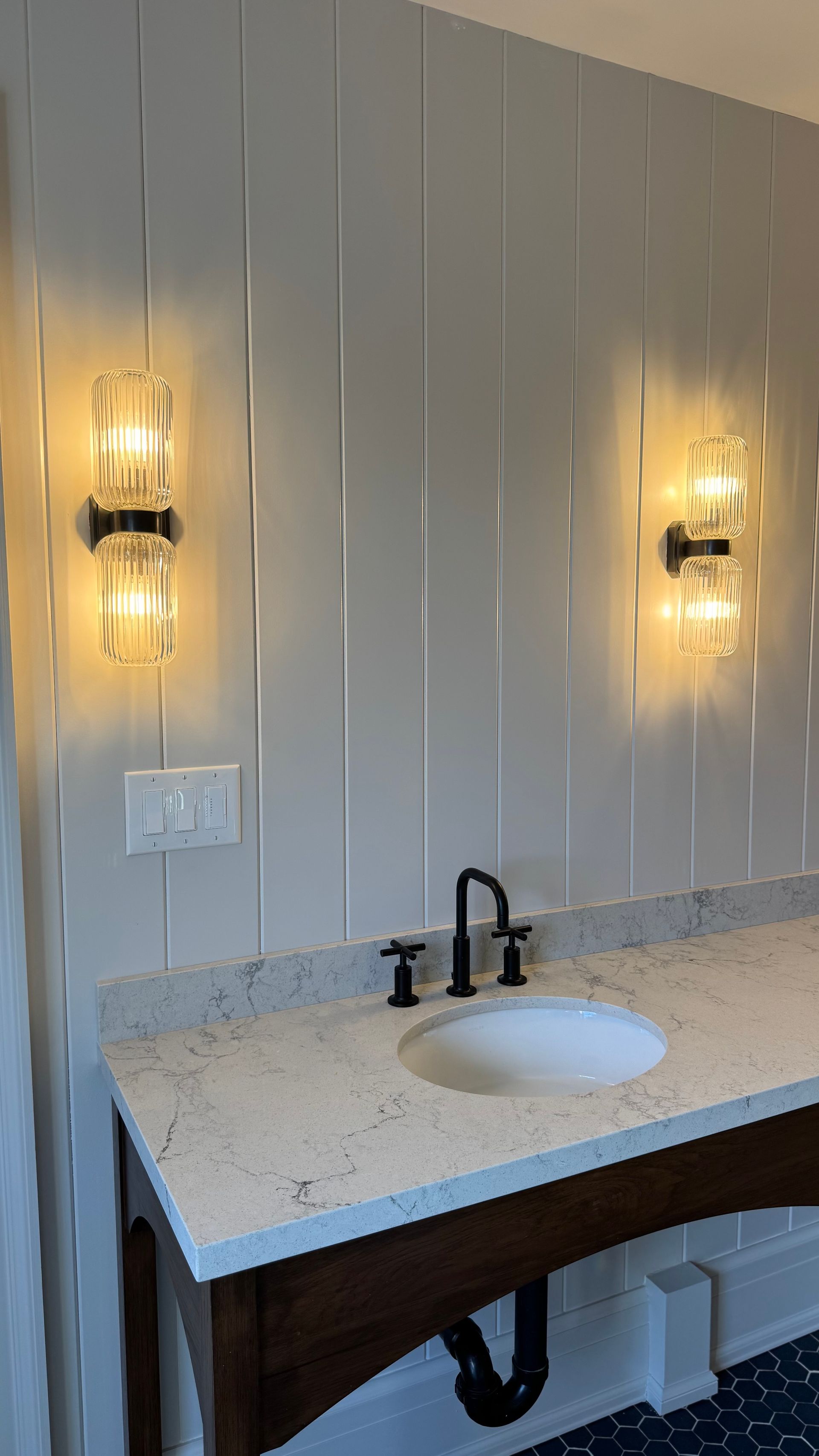 A bathroom with a sink and two lights on the wall.