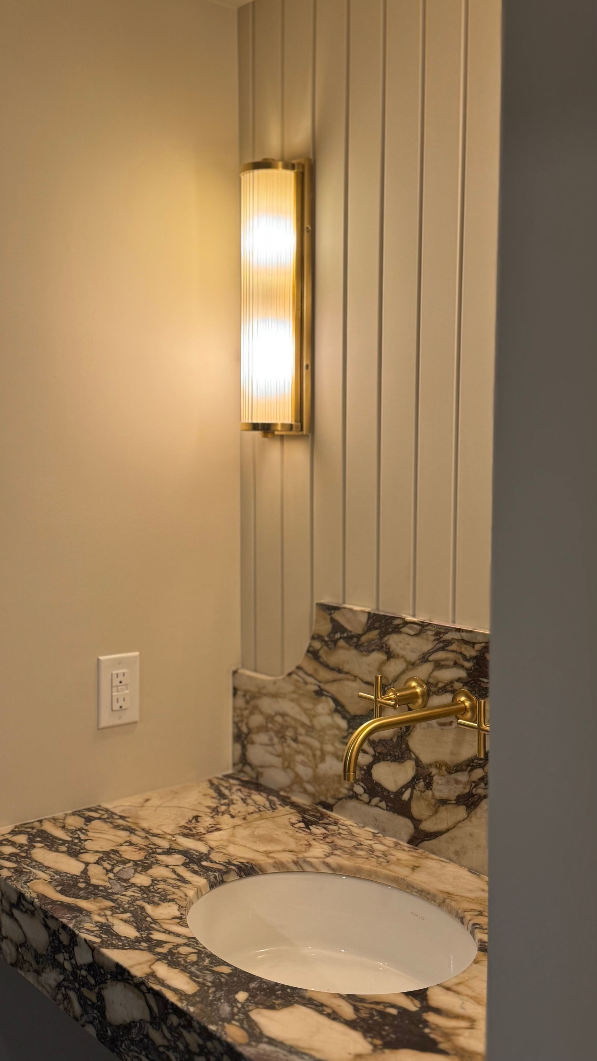 A bathroom with a sink and a light on the wall.