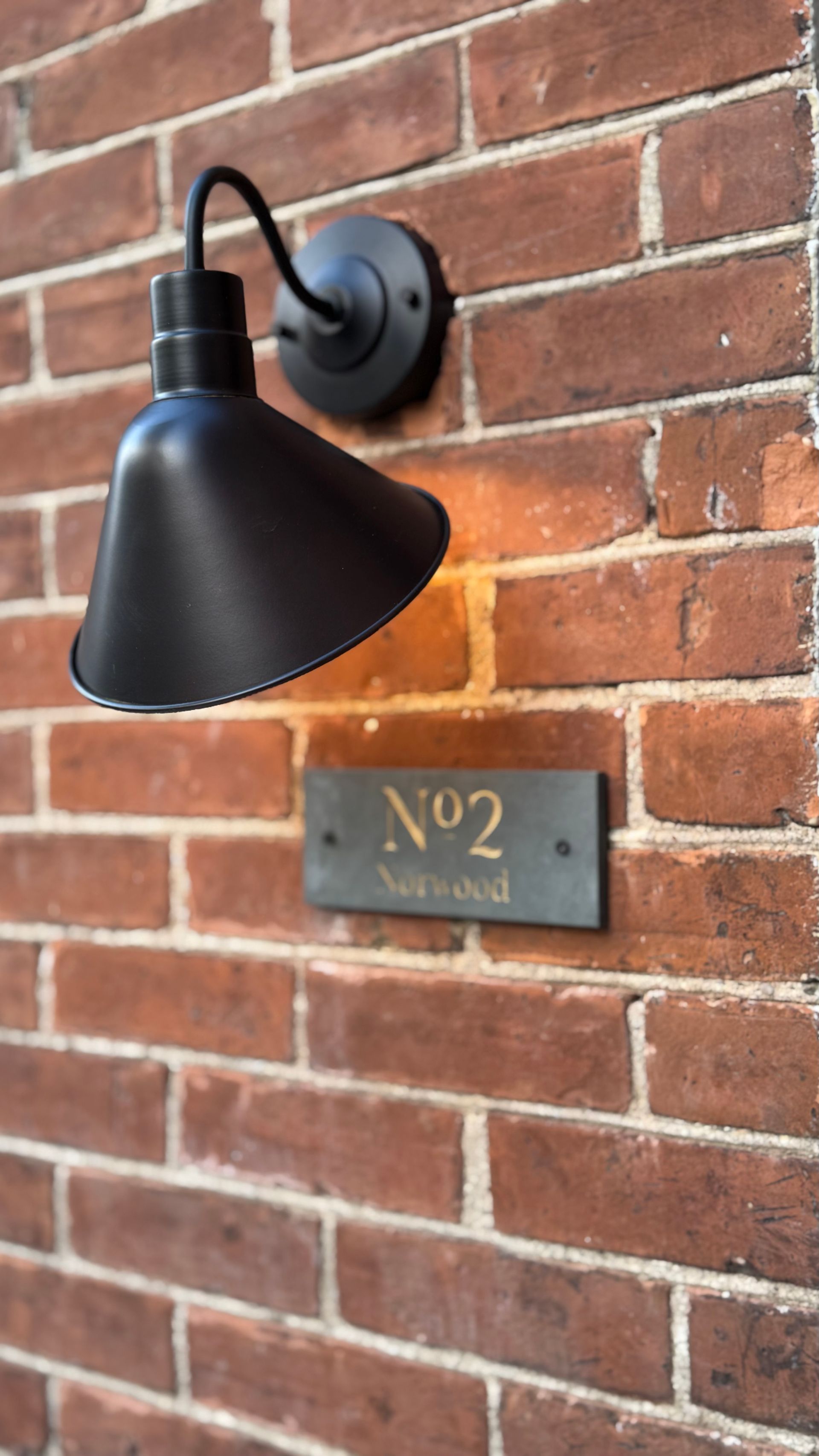 A brick wall with a lamp and a sign on it.