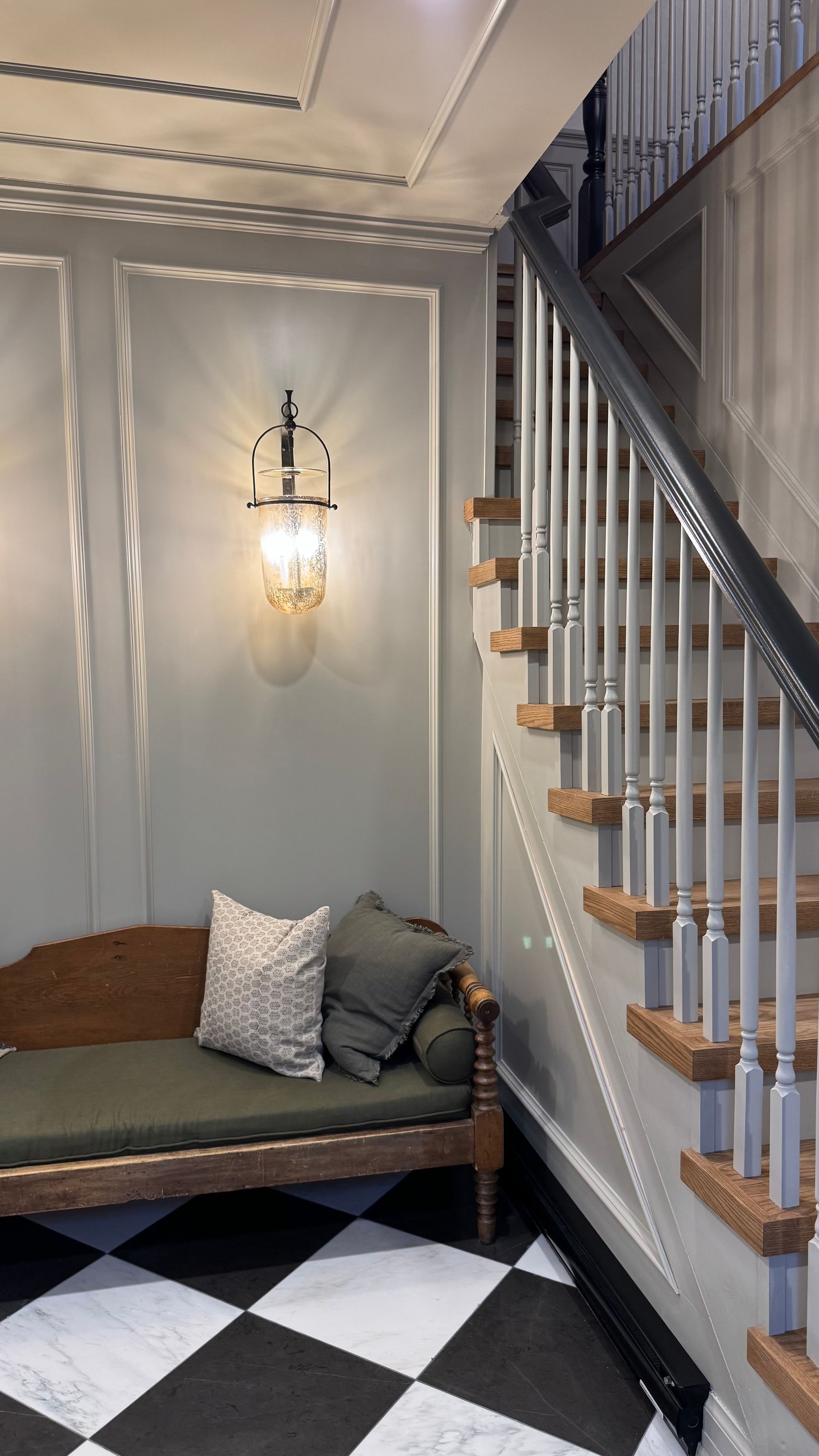 There is a bench in the corner of the room next to the stairs.