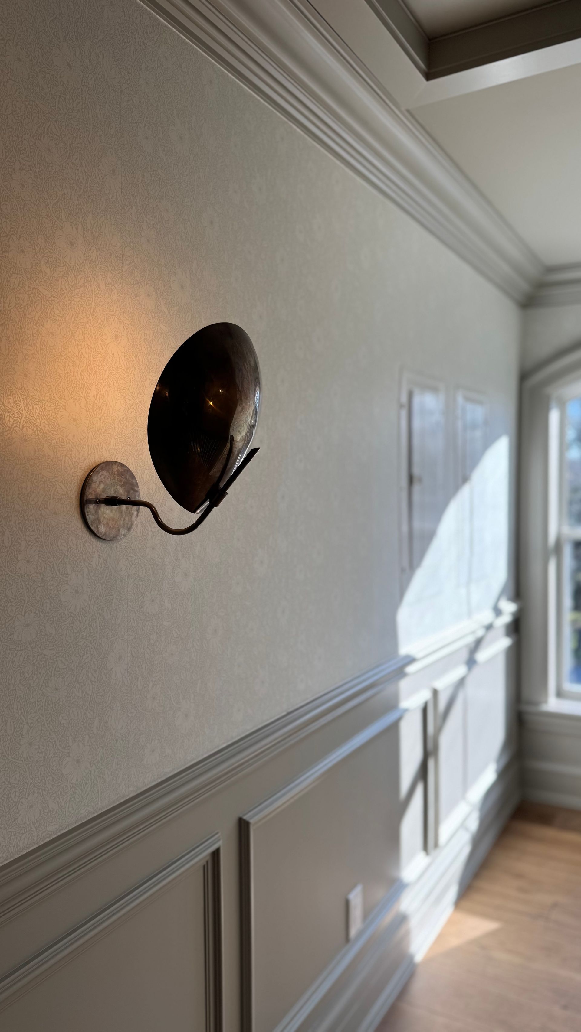 A hallway with a light on the wall and a window.