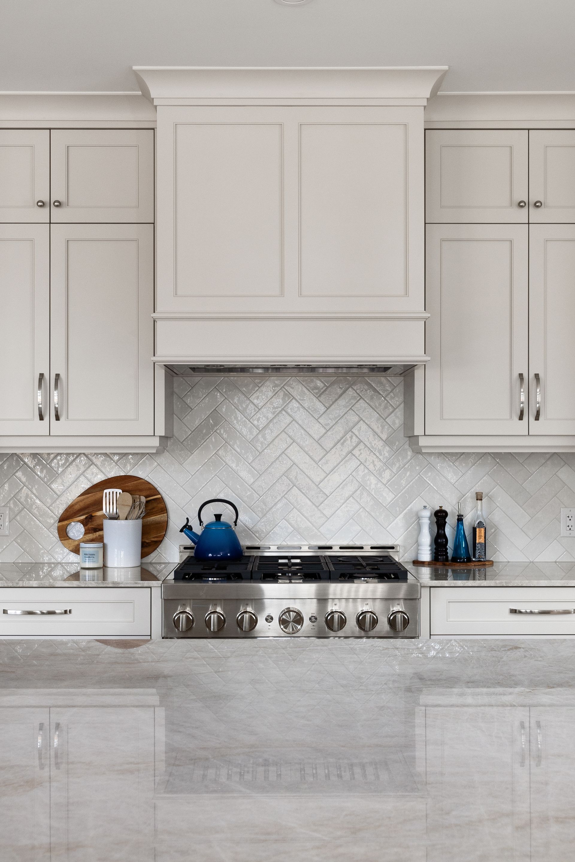 A kitchen with white cabinets , a stove , and a hood.