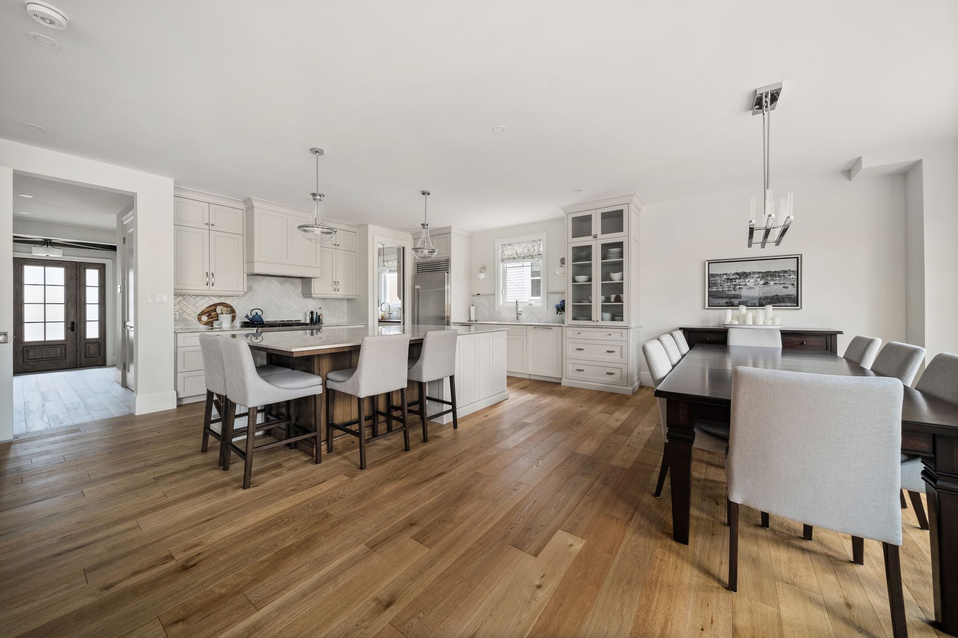 A kitchen and dining room in a house with hardwood floors and white cabinets.