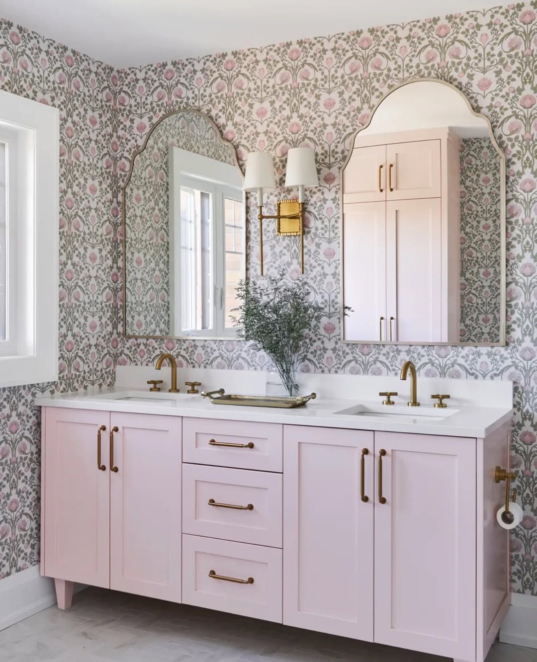 A bathroom with pink cabinets and a large mirror