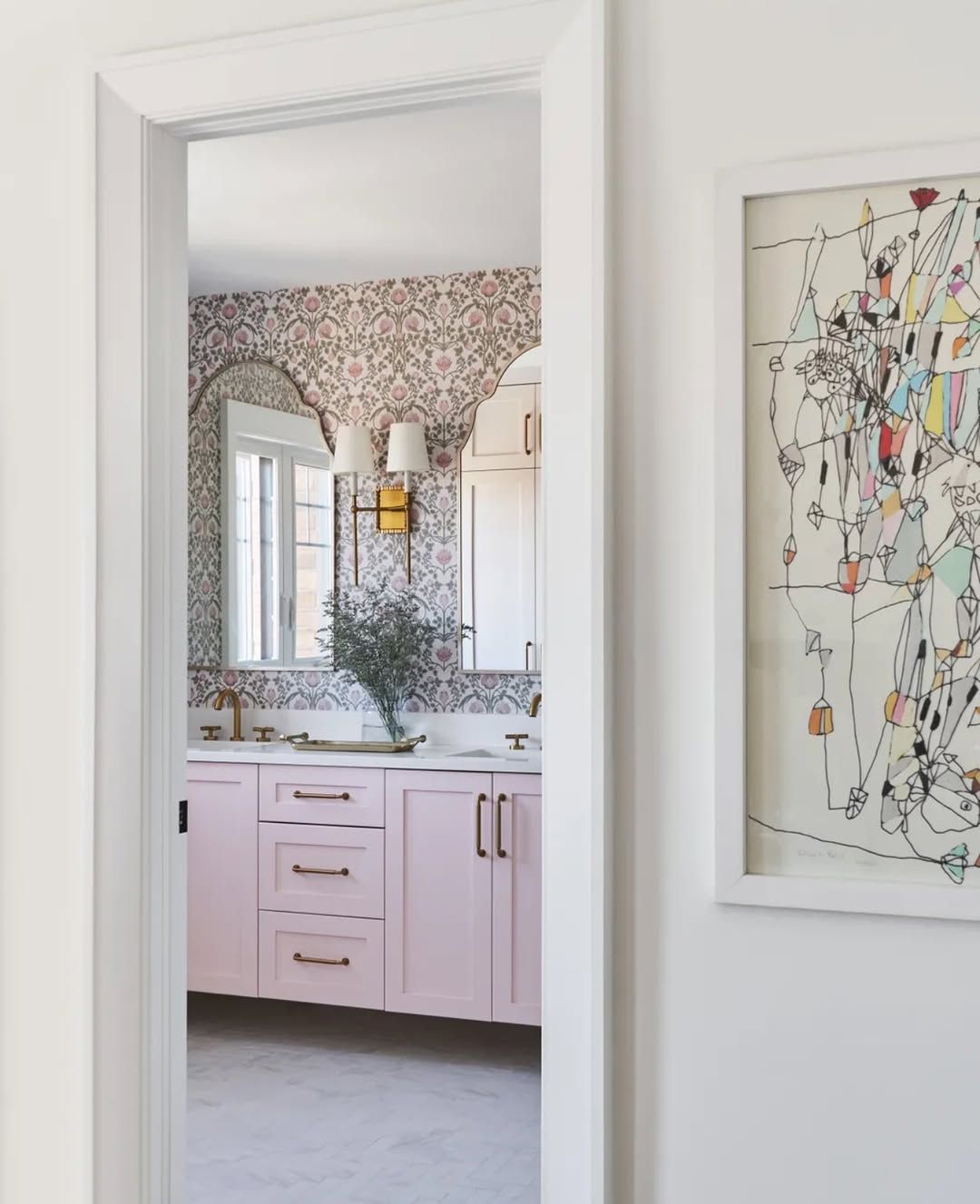 A bathroom with pink cabinets and a painting on the wall
