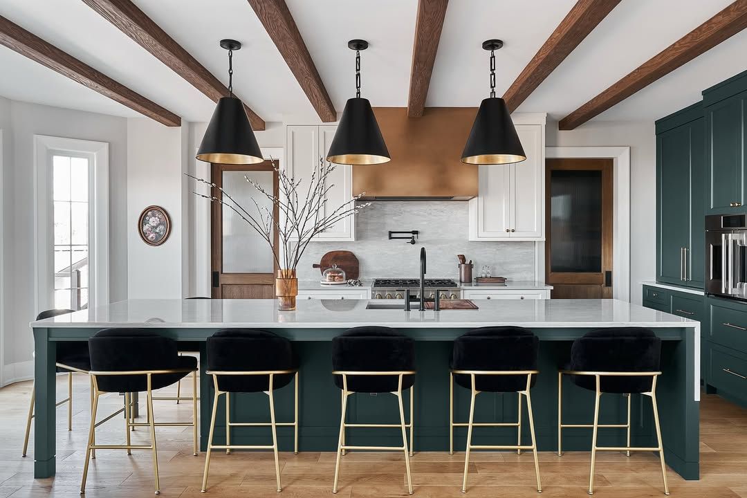 A kitchen with green cabinets , black stools , and a large island.