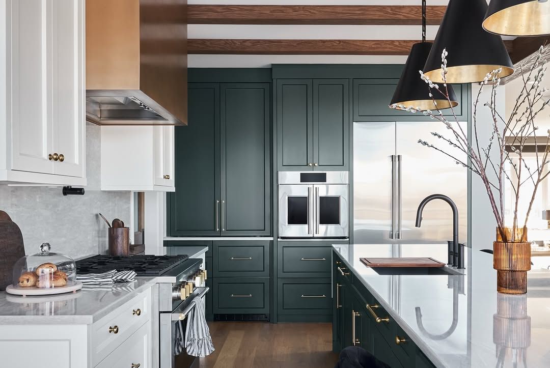 A kitchen with green cabinets and stainless steel appliances.