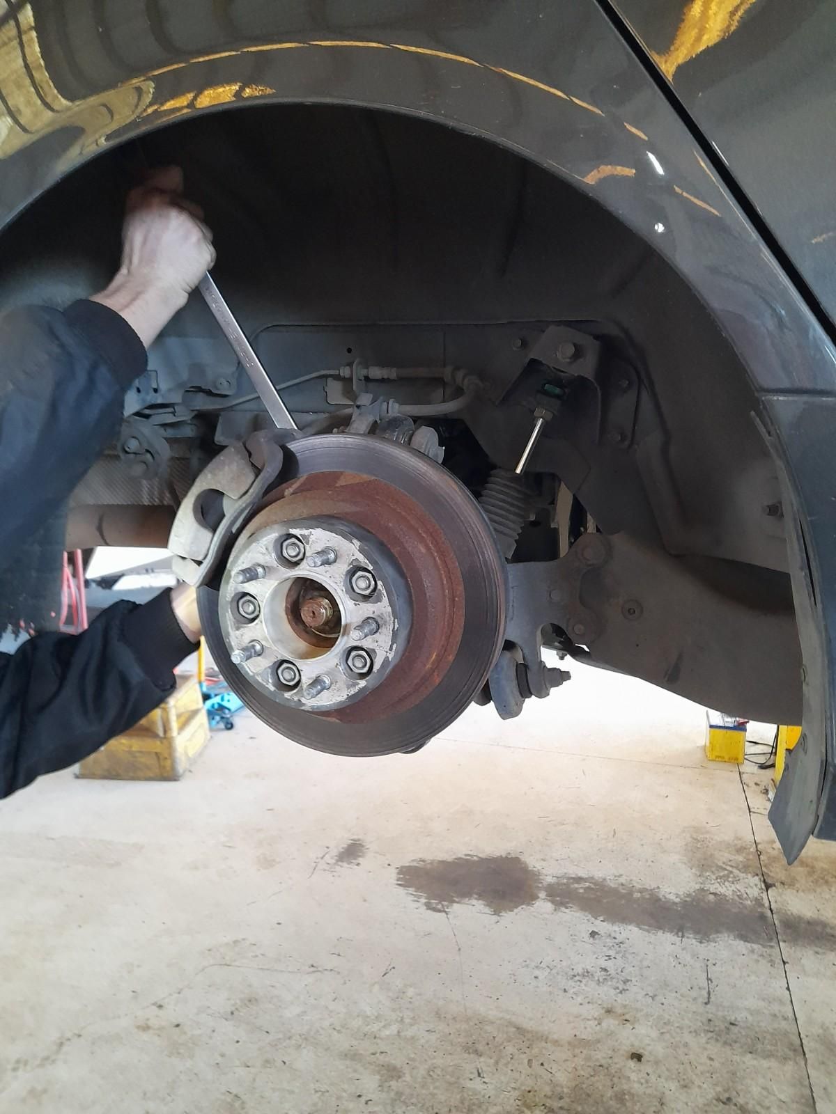 A Man Is Working on A Car Wheel with A Wrench — All Mechanical Services in South Murwillumbah, NSW