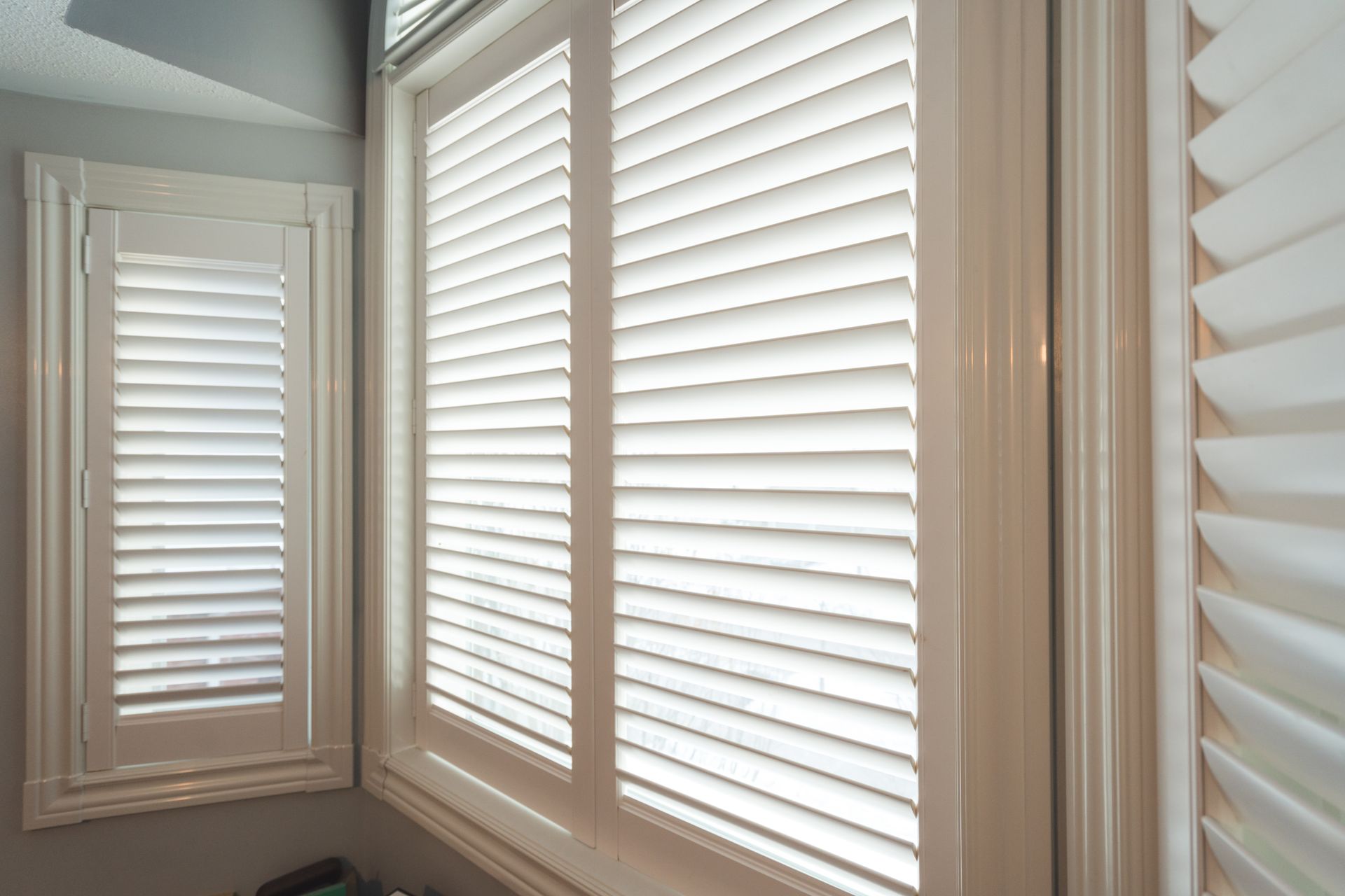 Beige window blinds covering multiple windows in a bright room