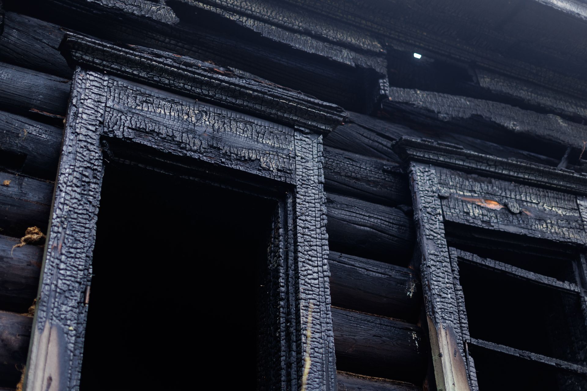 Charred window frames on a fire-damaged wooden building before Fire Restoration Services