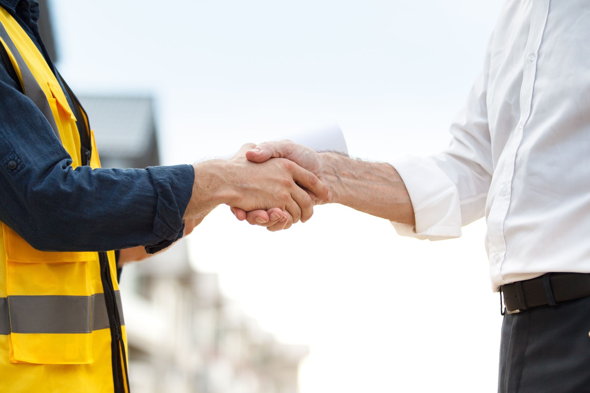 Person in safety vest shaking hands with person in white shirt outdoors Person in safety vest shaking hands with person in white shirt outdoors