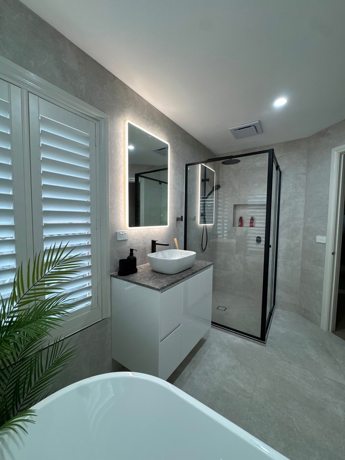 Modern bathroom with freestanding tub, tiled walls, and black rainfall shower head
