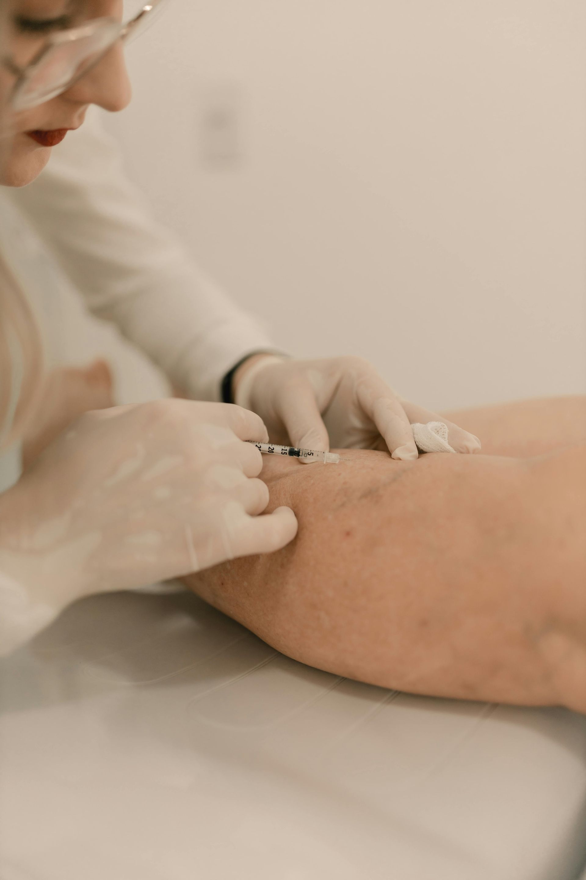 Un trabajador sanitario venda la herida de la pierna de un paciente con las manos enguantadas.