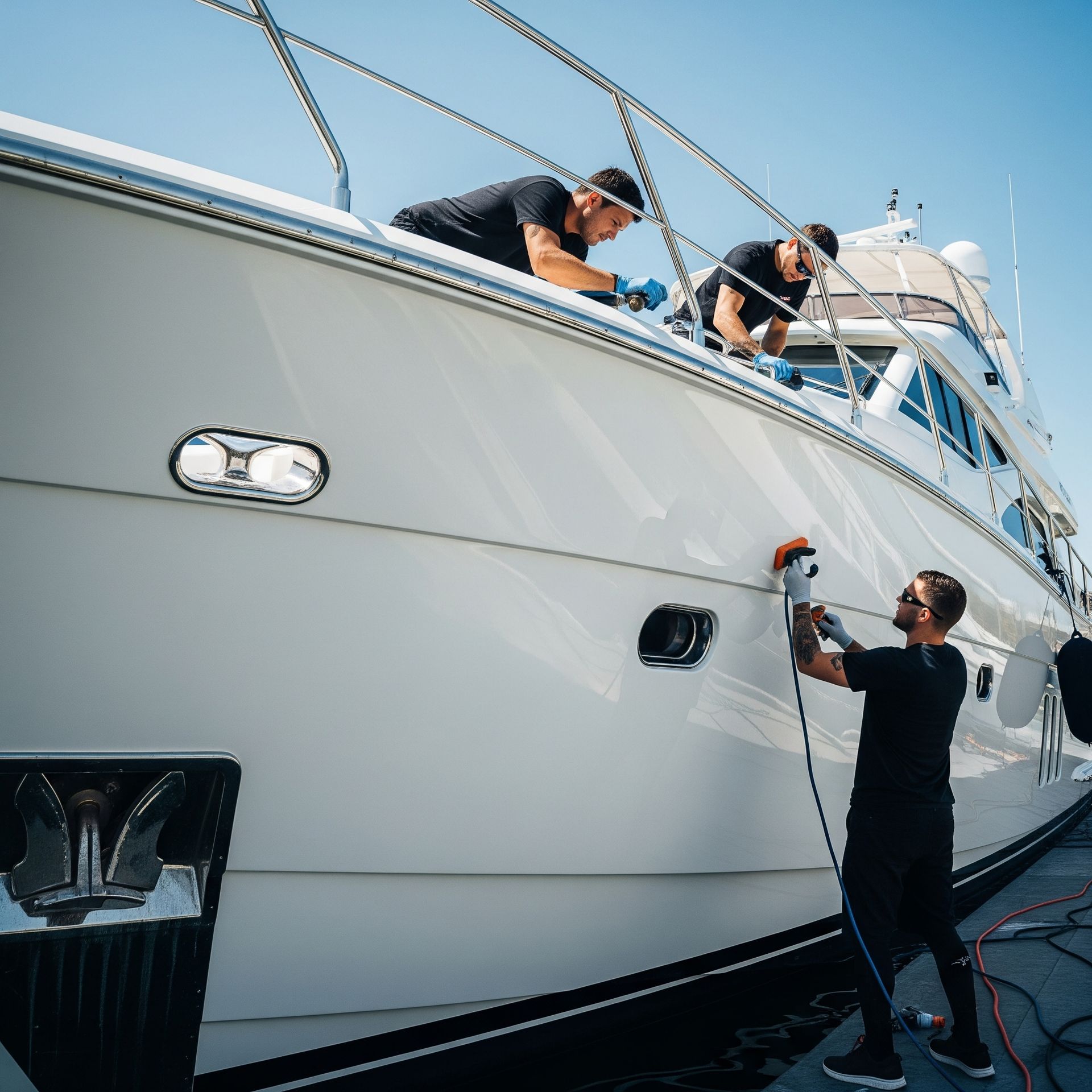 Professional yacht detailing crew cleaning and polishing a white luxury yacht in San Diego marina