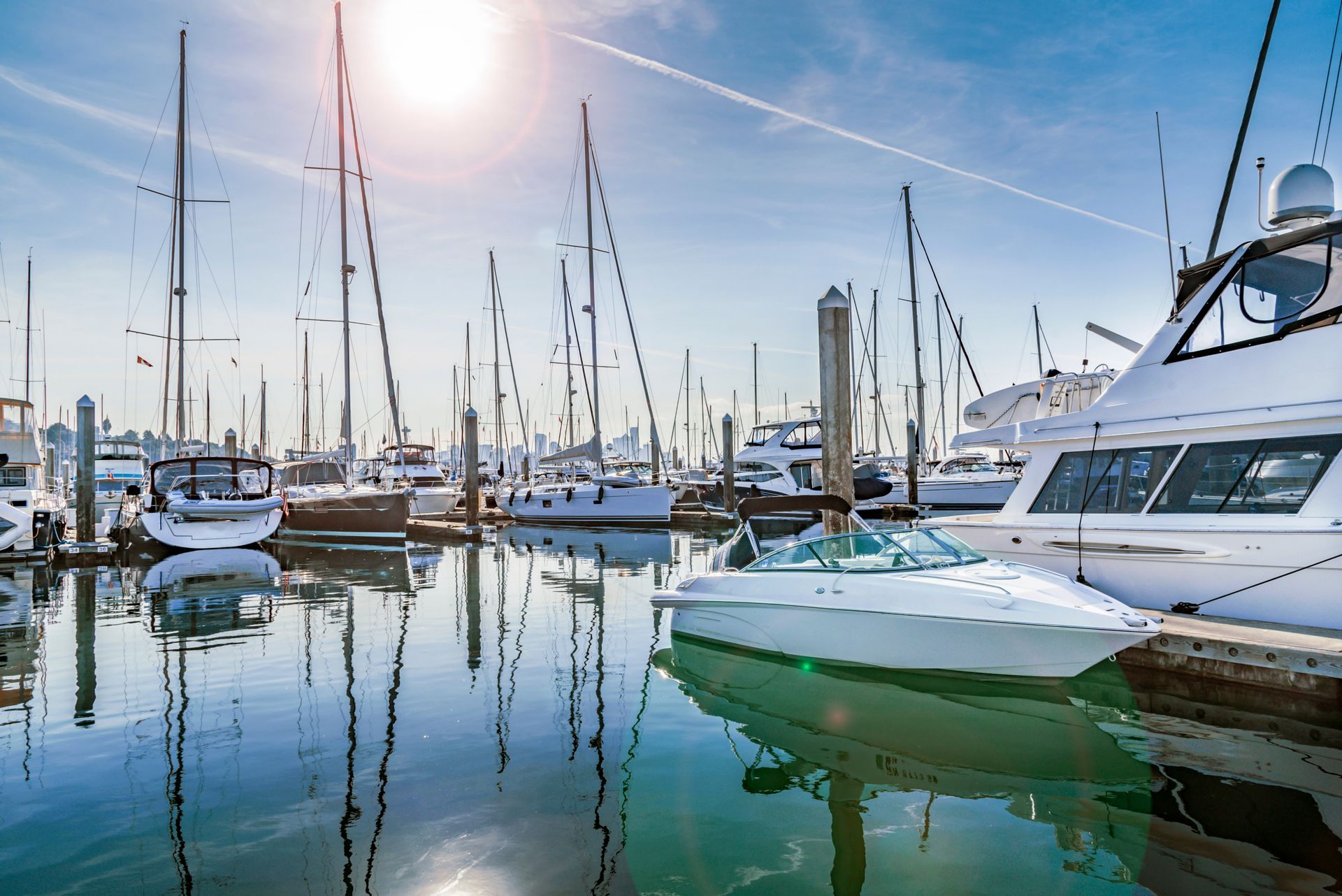 A row of boats are docked in a marina on a sunny day.