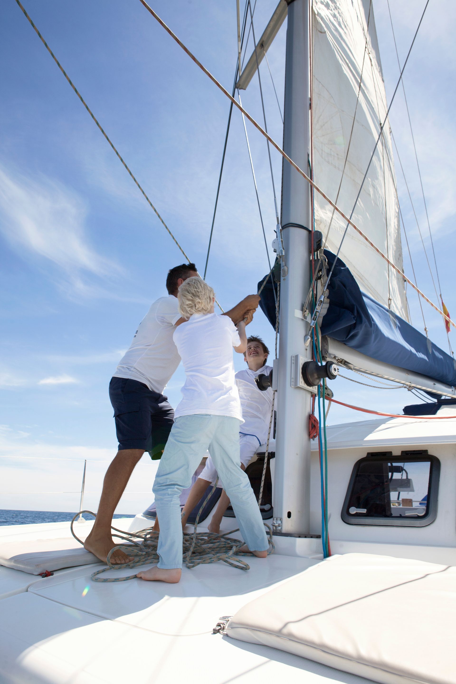 A group of people are working on a sailboat.