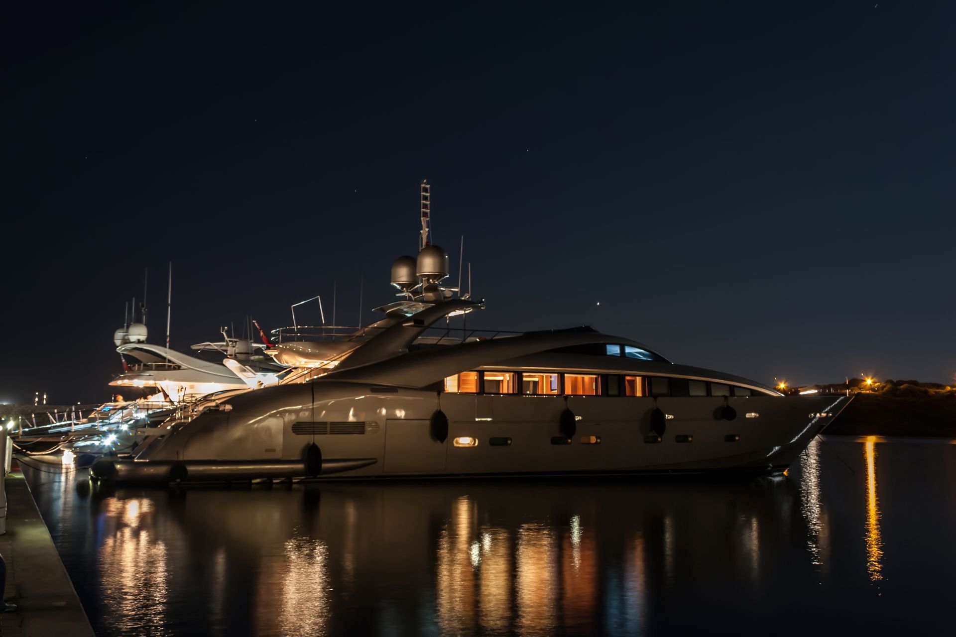 A large yacht is docked in a harbor at night.