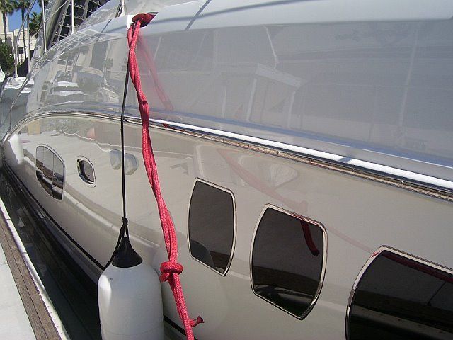Clean yacht hull with red dock line and protective fender