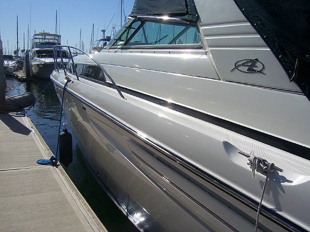 White motorboat docked beside a concrete marina pier