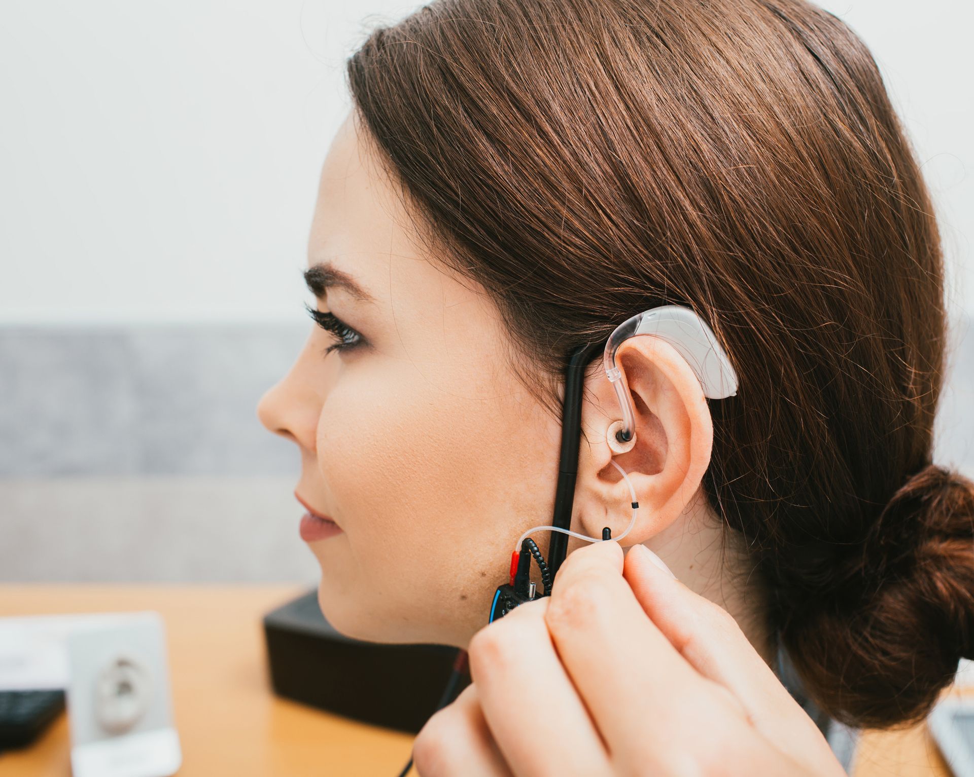 A person is being fitted with a hearing aid behind the ear. A person is being fitted with a hearing aid behind the ear.