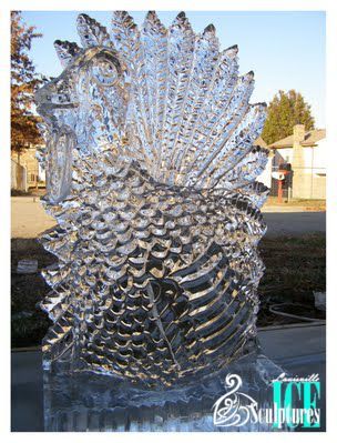 Clear ice sculpture of a fish with spiky fins outdoors on a sunny day