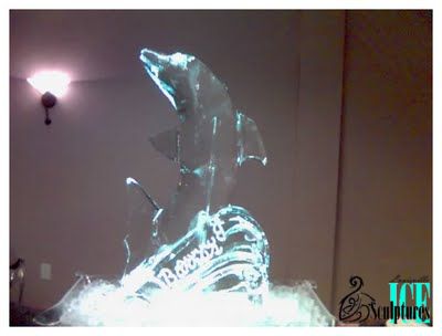 Glowing blue-white ice sculpture of a dolphin leaping in a dimly lit room