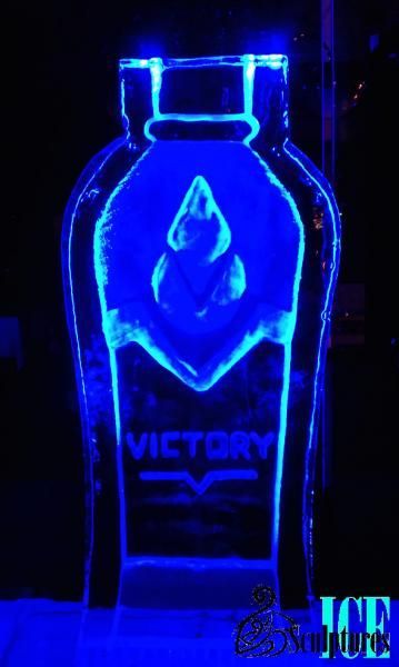 Blue neon-lit bottle-shaped logo with the word “VICTOR” on a dark background