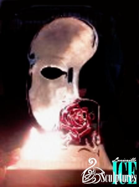 Abstract skull-like face in shadow, with a red rose over the mouth and bright light at the bottom.