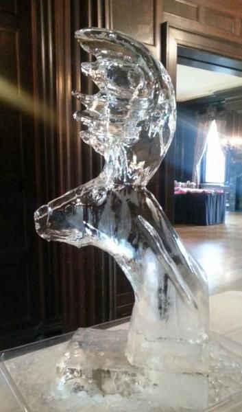 Clear ice sculpture of a dolphin on a table in a wood-paneled room