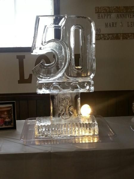 Clear glass 50th anniversary decoration on a table with a small candle glowing inside