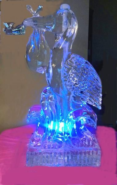 Blue-lit crystal deer figurine with antlers on a pink surface, glowing from the base