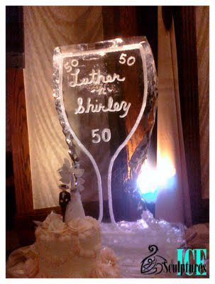 Personalized 50th birthday ice sculpture with “Luther” written on it, lit in a dim room