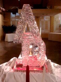 Ice sculpture on a table, lit pink, in a banquet hall