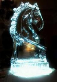 Heart-shaped ice sculpture on a pedestal, lit from below, with floral decoration at the base.