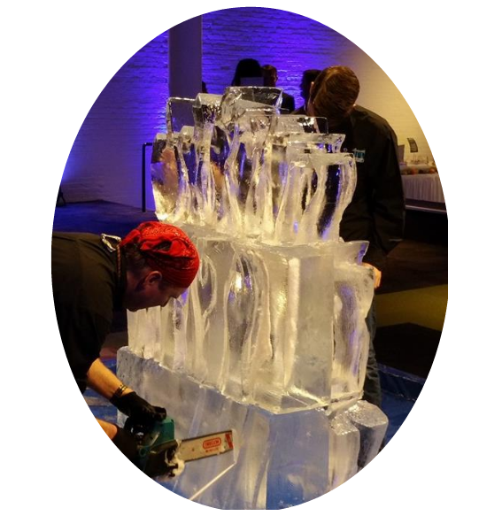 Heart-shaped ice sculpture on a pedestal, lit from below, with floral decoration at the base.