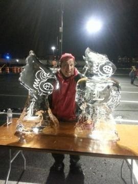 Person posing between two illuminated ice sculptures at a night event
