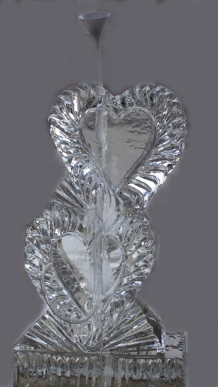Clear glass decorative sculpture with an ornate heart-shaped design on a pedestal, topped by a small funnel.