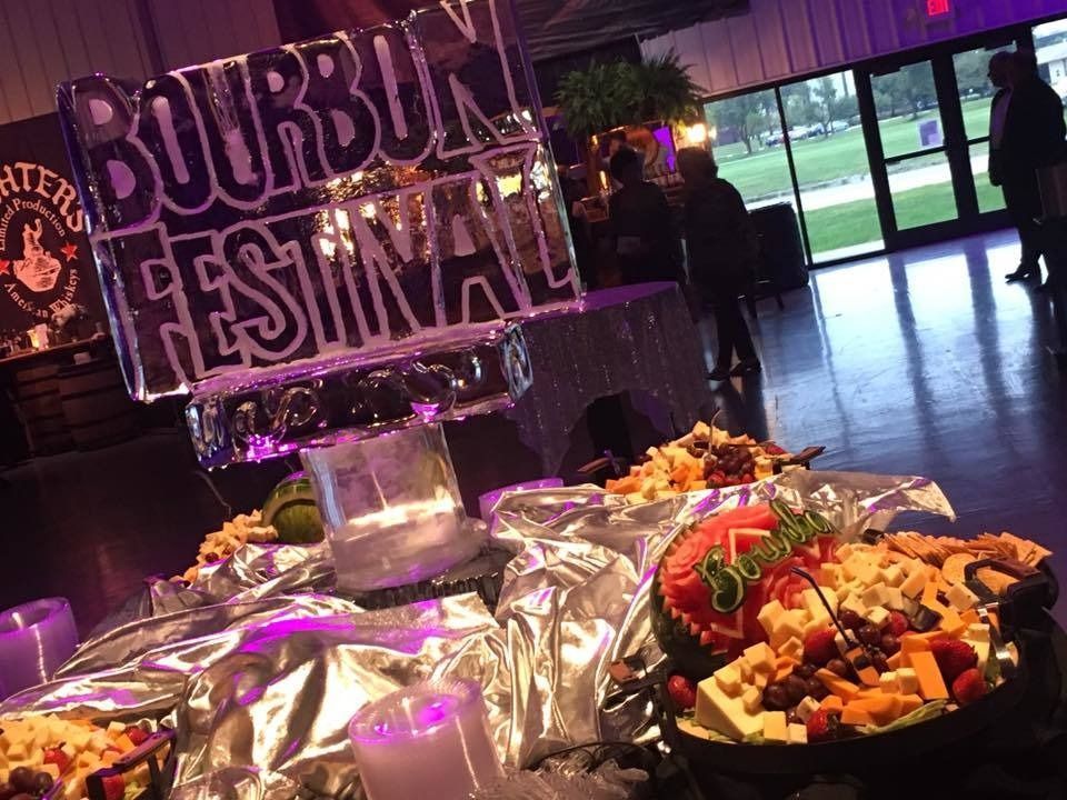 Bourbon Festival buffet with trays of food and a purple-lit sign in an indoor venue