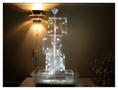Lit translucent stacked sculpture with glowing white circles on a table beside a wall lamp.