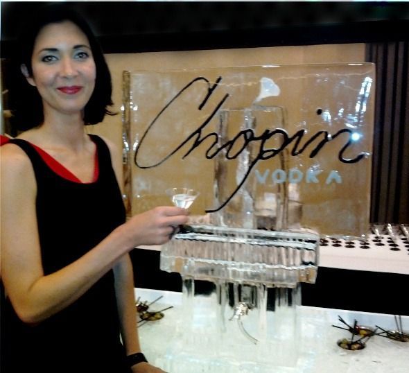 Woman in a black and red dress beside an ice sculpture displaying the Chopin Vodka logo.