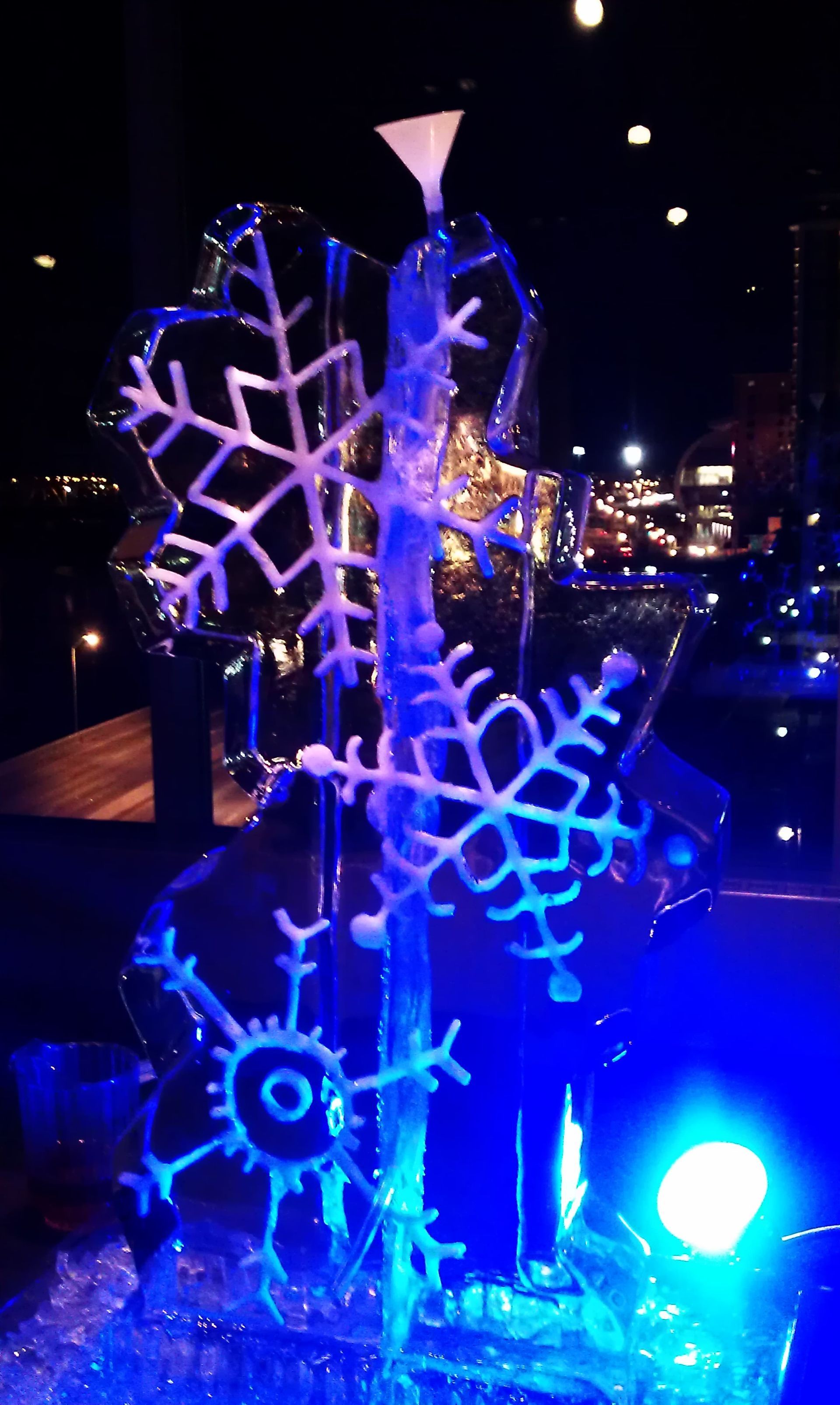 Illuminated snowflake holiday decorations glowing blue and purple at night outdoors