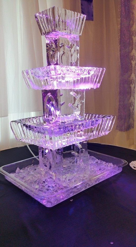 Purple-lit four-tier decorative fountain on a dark table with a waterfall effect