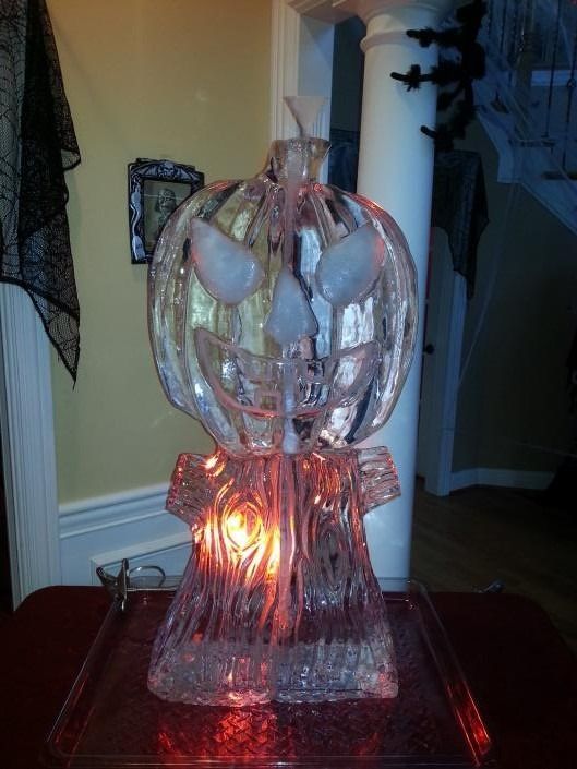 Carved pumpkin-shaped glass lamp glowing orange on a table in a dim room