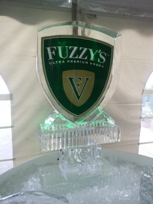 Green Fuzzy’s beer sign on a clear ice base, with a shield logo and a large “V” in the center