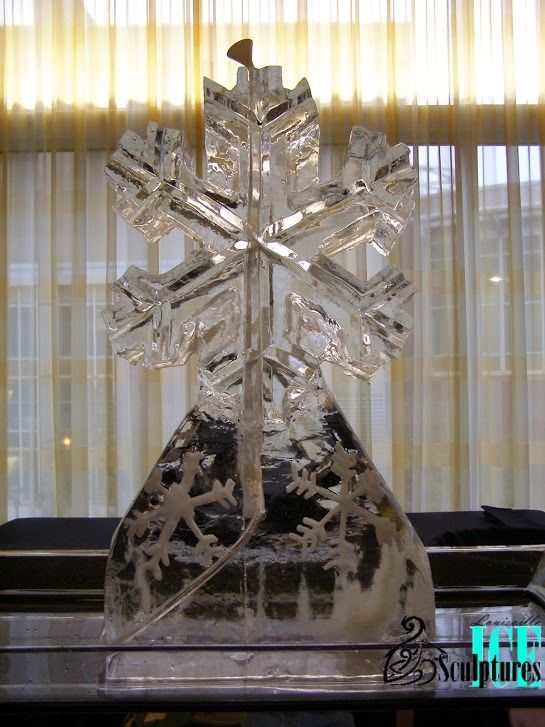 Crystal snowflake sculpture on a round base, lit by sunlight through sheer curtains.