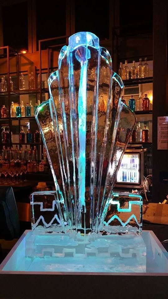 Glowing blue ice sculpture shaped like a fountain in a dimly lit bar or restaurant interior