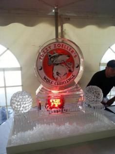 Ice sculpture display with a circular logo and lit red centerpiece under a tent.