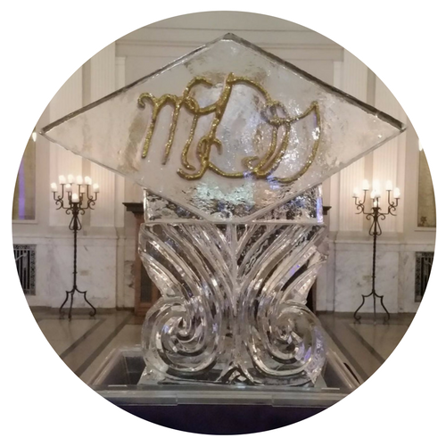 Heart-shaped ice sculpture on a pedestal, lit from below, with floral decoration at the base.