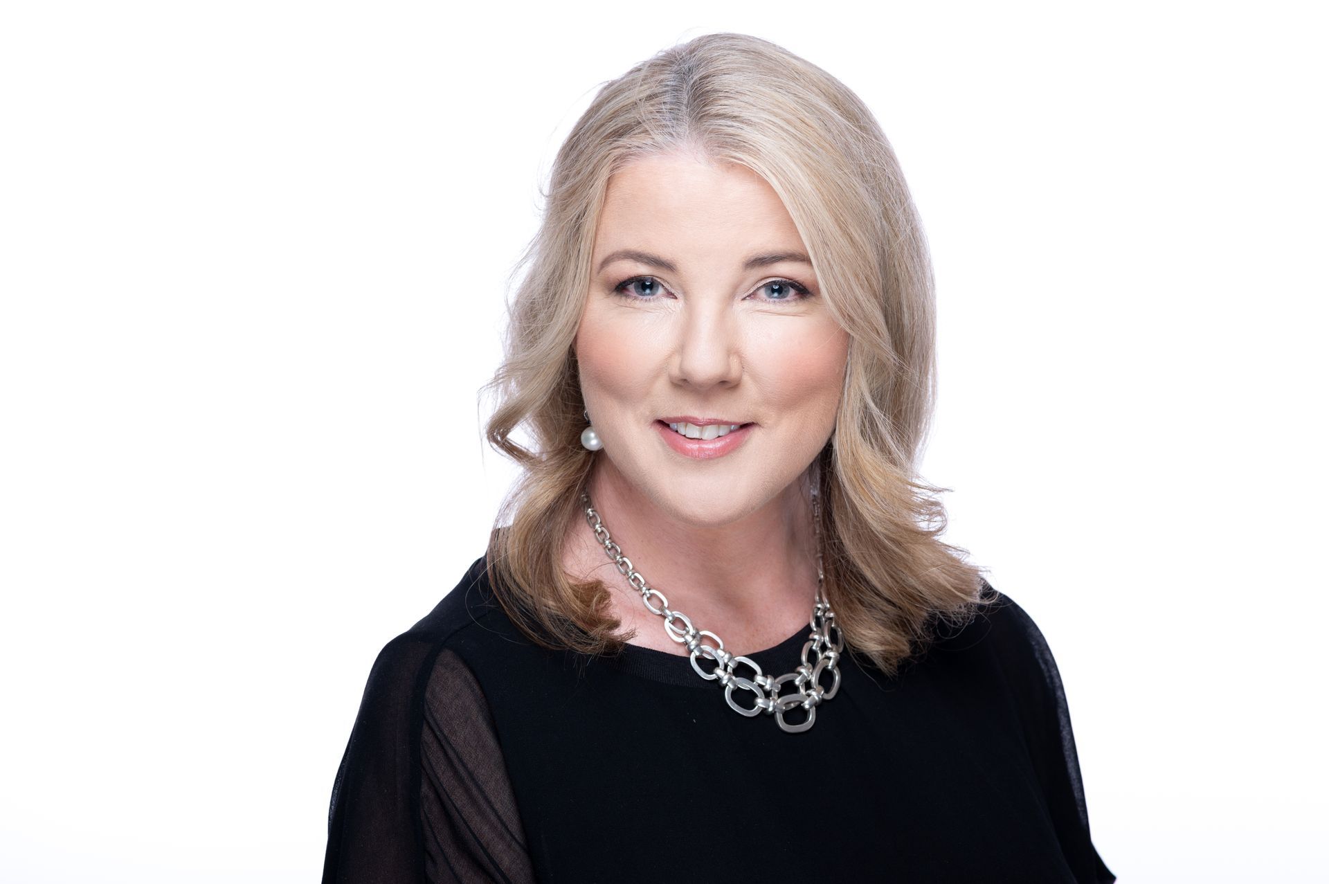 A woman, Kim Sutton, Carmen and Co Founder & Director and Lead Consultant, is wearing a black dress and a silver necklace is smiling for the camera - Carmen & Co Consulting Strategic Consulting in Southeast Queensland